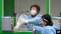 Medical workers wearing protective gear spray disinfectant at a temporary screening clinic for coronavirus in Seoul, South Korea on Dec. 10, 2021.