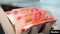 Des billets chinois de 100 yuans dans une machine de comptage de la une succursale d'une banque commerciale à Pékin, en Chine, le 30 mars 2016. 