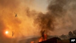 FILE - In this Sunday, Aug. 5, 2018, file photo, a helicopter drops water on a burning hillside during the Ranch Fire in Clearlake Oaks, Calif. Authorities say a rapidly expanding Northern California wildfire burning over an area the size of Los Angeles has become the state's largest blaze in recorded history. It's the second year in a row that California has recorded the state's largest wildfire. (AP Photo/Josh Edelson, File)