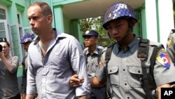 Philip Blackwood, manajer V Gastro Bar (kiri) dikawal ketat oleh polisi di pengadilan Rangoon, Myanmar, 17 Maret 2015. (AP Photo/Khin Maung Win)