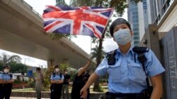 A pro-democracy supporter waves a British flag as police officers stand guard outside a court in Hong Kong Thursday, April 1, 2021. (AP Photo/Vincent Yu)