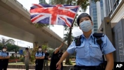 A pro-democracy supporter waves a British flag as police officers stand guard outside a court in Hong Kong Thursday, April 1, 2021. (AP Photo/Vincent Yu)