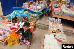 FILE - A boy dressed as United Wa State Army (UWSA) soldier, sits in a market at Mongmao, Wa territory in northeast Myanmar, Oct. 1, 2016.