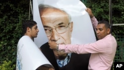 Workers uninstall a billboard showing presidential candidate Ahmed Shafiq in Cairo.