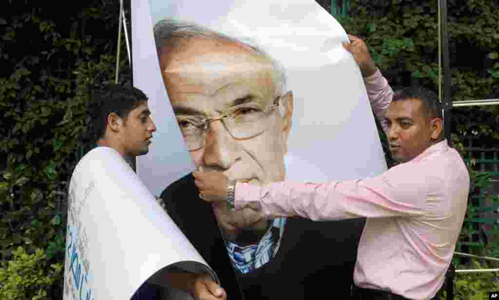 Workers uninstall a billboard showing presidential candidate Ahmed Shafiq in Cairo.