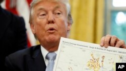 FILE - President Donald Trump holds up a map as he speaks about Harvey in the Oval Office of the White House, Sept. 1, 2017, in Washington. 