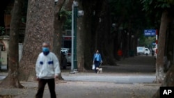 A woman walks her dog on a quiet street in Hanoi, Vietnam, April 1, 2020.