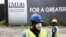 FILE - Construction workers stand in front of a 1Malaysia Development Berhad (1MDB) billboard at the Tun Razak Exchange development in Kuala Lumpur, Malaysia.