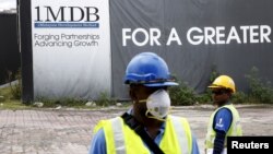 Para pekerja bangunan di depan papan iklan 1Malaysia Development Berhad (1MDB) di proyek pembangunan Tun Razak Exchange di Kuala Lumpur, Malaysia, 3 Februari 2016. (Foto: Reuters)