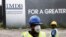 FILE - Construction workers stand in front of a 1Malaysia Development Berhad (1MDB) billboard at the Tun Razak Exchange development in Kuala Lumpur, Malaysia.