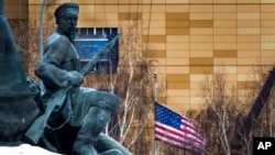 FILE - The U.S. Embassy with its national flag is seen behind a monument to the Workers of 1905 Revolution in Moscow, Russia, Dec. 30, 2016.