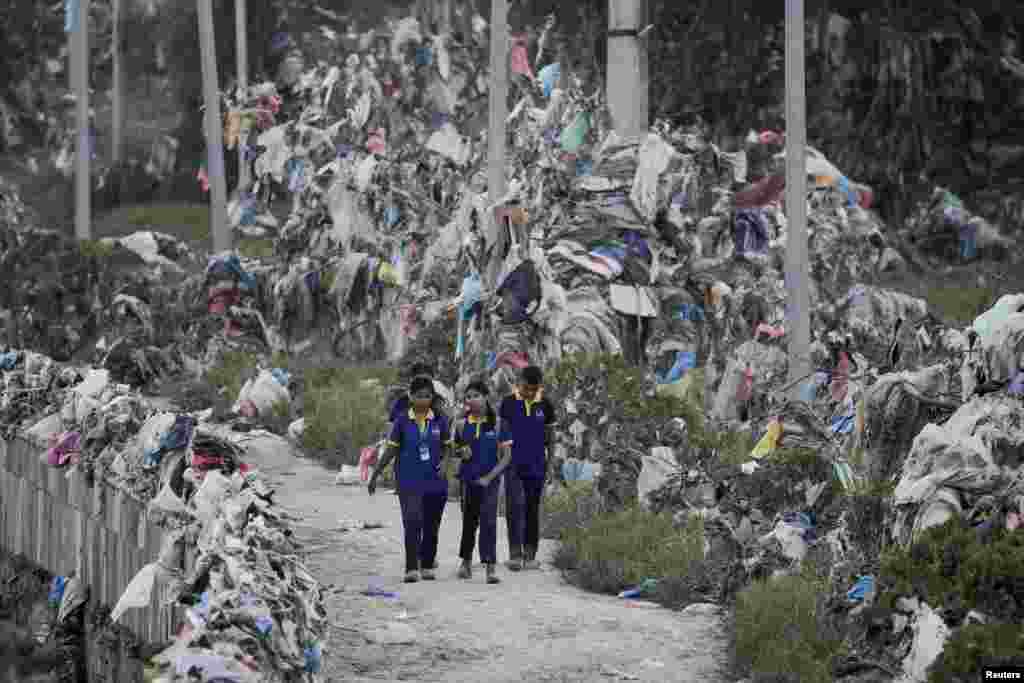 Students walk past the debris, mostly plastic waste, as the flood water recedes from the bank of Bagmati river following the deadly flood due to heavy rains, in Kathmandu, Nepal.