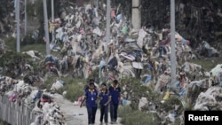 Students walk past the debris, mostly plastic waste, as the flood water recedes from the bank of Bagmati river following the deadly flood due to heavy rains, in Kathmandu, Nepal.