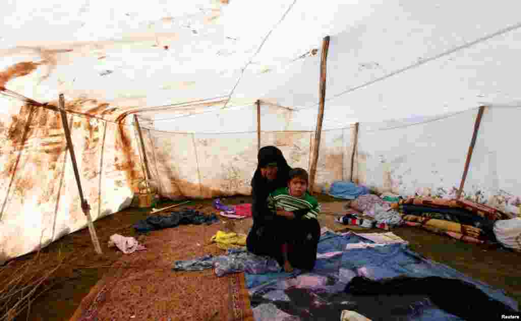 A Syrian refugee woman and her child sit in her makeshift tent in the town of Viransehir, southeast Turkey, February 10, 2013. 