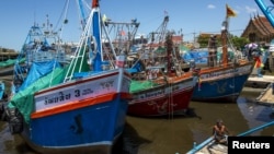 A fisherman man sits on a pier near docked fishing boats at a port in Thailand July 1, 2015. Thai fishermen went on strike to protest regulations aimed at clamping down on illegal fishing. 