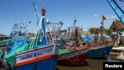 Kapal-kapal nelayan berlabuh setelah operasi-operasi penangkapan ikan dihentikan, di sebuah pelabuhan di provinsi Samut Sakhon, Thailand.