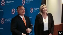 Leader of French far-right party Rasemblement National and candidate for France's presidential elections Marine Le Pen ,right, and Hungarian Prime Minister Viktor Orban ,left, pose before the meeting of Leaders of European conservative and right-wing parties, Warsaw, Dec.4, 2021.