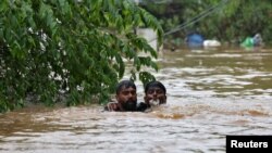 FILE - A man rescues a drowning man from a flooded area after the opening of Idamalayr, Cheruthoni and Mullaperiyar dam shutters following heavy rains, on the outskirts of Kochi, India August 16, 2018.