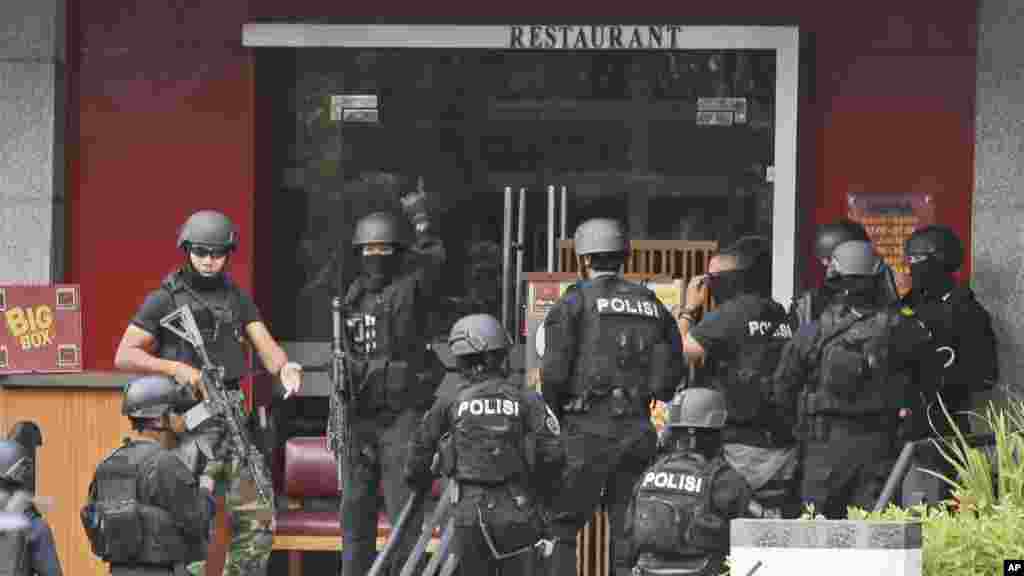 Police officers gather outside a Pizza Hut restaurant next door to a Starbucks cafe which was attacked in Jakarta, Indonesia Thursday, Jan. 14, 2016. Attackers set off explosions at a Starbucks cafe in a bustling shopping area in Indonesia's capital and waged gunbattles with police Thursday, leaving bodies in the streets as office workers watched in terror from high-rise windows