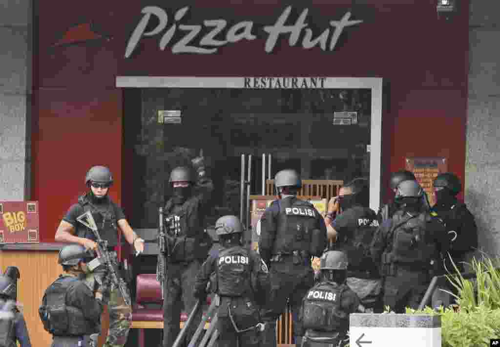 Police officers gather outside a Pizza Hut restaurant next door to a Starbucks cafe which was attacked in Jakarta.