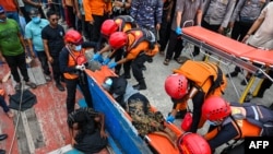 Anggota Basarnas tampak mengangkut seorang warga Rohingya yang sakit dari sebuah perahu di wilayah Labuhan Haji, Aceh selatan, pada 20 Oktober 2024. (Foto: AFP/Chaideer Mahyuddin)