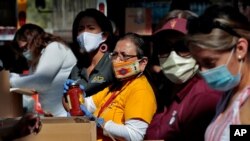 Volunteers prepare donations for delivery to those affected by COVID-19 on tribal lands June 25, 2020, in Tempe, Ariz. 