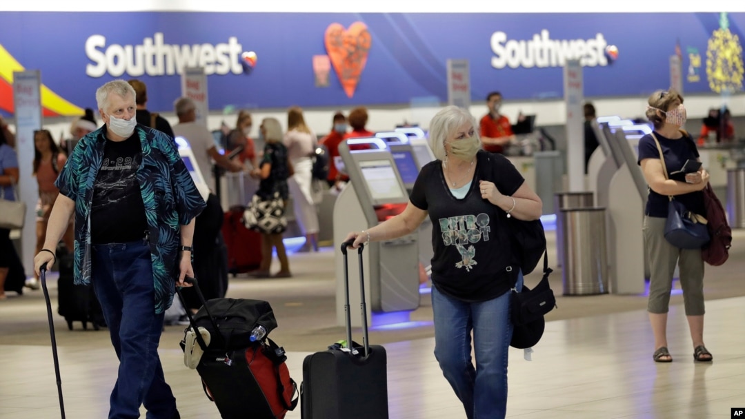 Pasajeros usando mascarillas caminan por el aeropuerto de Tampa, Florida. Aerolíneas como United, American, Delta y otras están exigiendo ahora usar mascarillas.