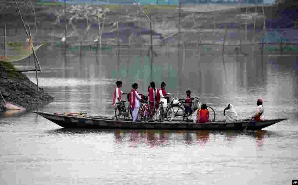 School children ride on a boat with their bicycles to cross the river Brahmaputra in Kasoshila village on the outskirts of Gauhati, India.