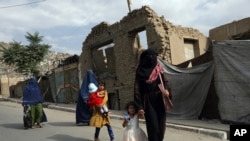 Mujeres afganas en Kabul recorren una calle enfundadas completemente en una burka, como reclaman los talibanes desde que tomaron el poder, el 14 de agosto de 2021.