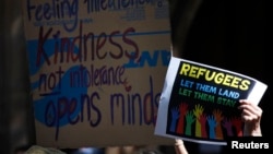 FILE - Protesters hold placards at the 'Stand up for Refugees' rally held in central Sydney. Protesters set fires at an Australian-run detention center on Christmas Island following the death of an Iranian-born asylum seeker.