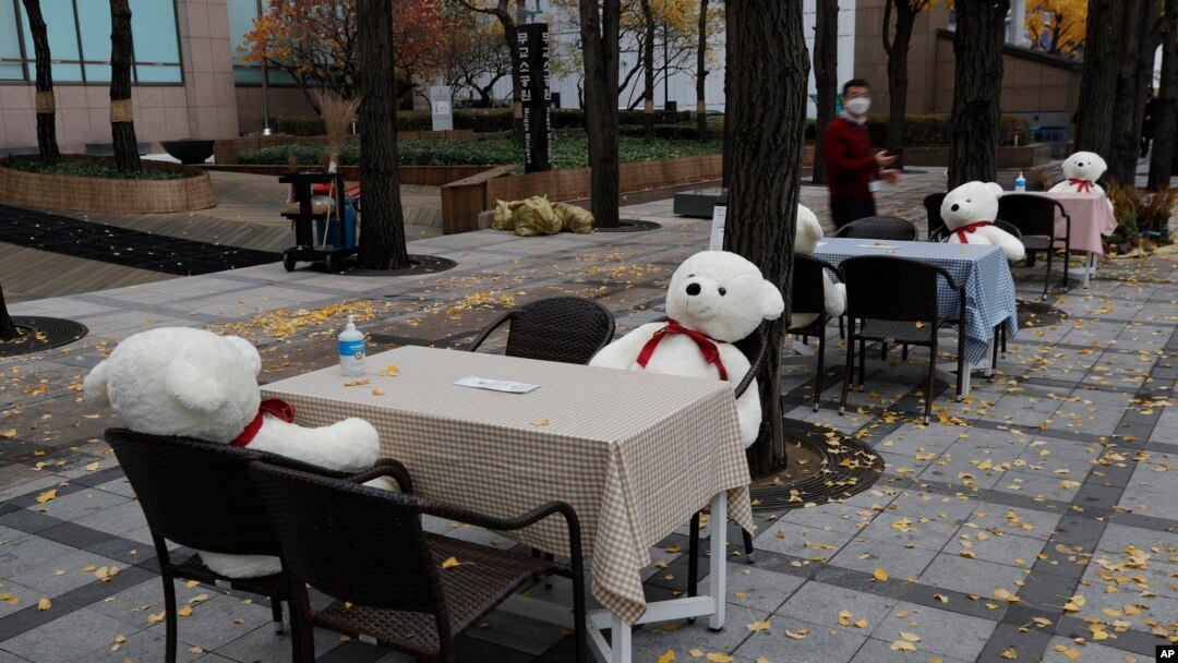 Meja dan kursi diletakkan dengan hand sanitizer dan boneka mainan untuk menjaga jarak sosial di pusat kota Seoul, Korea Selatan, Rabu, 18 November 2020. (Foto: AP)