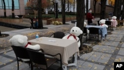 Meja dan kursi diletakkan dengan hand sanitizer dan boneka mainan untuk menjaga jarak sosial di pusat kota Seoul, Korea Selatan, Rabu, 18 November 2020. (Foto: AP)