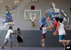Boys plays beside images of former NBA basketball player Kobe Bryant at the "House of Kobe" basketball court in Valenzuela, north of Manila, Philippines on Monday, Jan. 27, 2020.