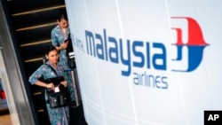 Awak penerbangan Malaysia Airlines menuju aula keberangkatan di Bandara Internasional Kuala Lumpur. (AP/Joshua Paul)