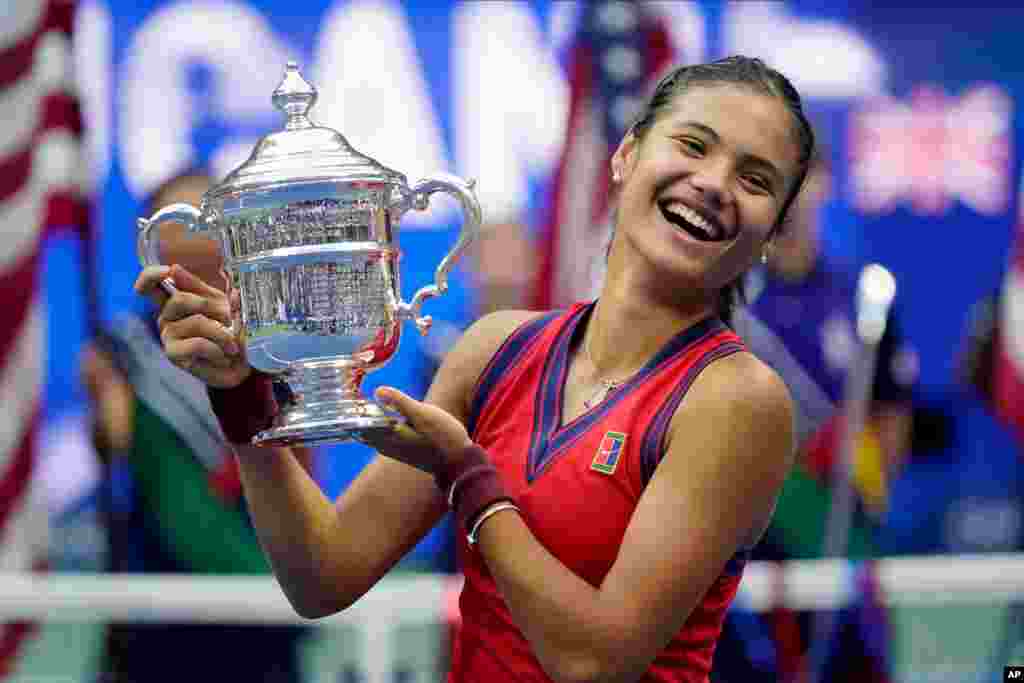 Remaja putri Inggris Emma Raducanu (18 tahun), mengangkat trofi juara tunggal putri setelah mengalahkan Leylah Fernandez (19 tahun), dari Kanada, pada final kejuaraan tenis grand slam AS Terbuka, Sabtu (11/9) di New York. (Foto AP/Seth Wenig)