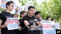 Cameron Kasky, center, speaks during a news conference, Monday, June 4, 2018, in Parkland, Florida, one day after graduating from high school. His group has announced a bus tour to "get young people educated, registered and motivated to vote." (AP Photo/Wilfredo Lee)