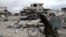 FILE - A man walks with his bicycle at a damaged site in the besieged town of Douma, Eastern Ghouta, near Damascus, Syria, March 30, 2018.