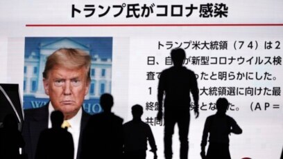 Người dân Nhật đi ngang qua một màn ảnh truyền hình tại Tokyo loan tin Tổng thống Donald Trump xét nghiệm dương tính với virus corona, ngày 2/10/2020.