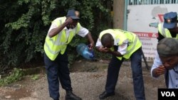 Guards at a nearby building at University Road in central Nairobi wash away tear gas. (M. Yusuf/VOA)