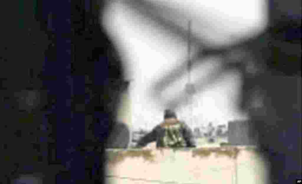 A man in military fatigues is seen on a rooftop in Homs in this still image from a video uploaded to a social media website, May 6, 2011. (Reuters image)