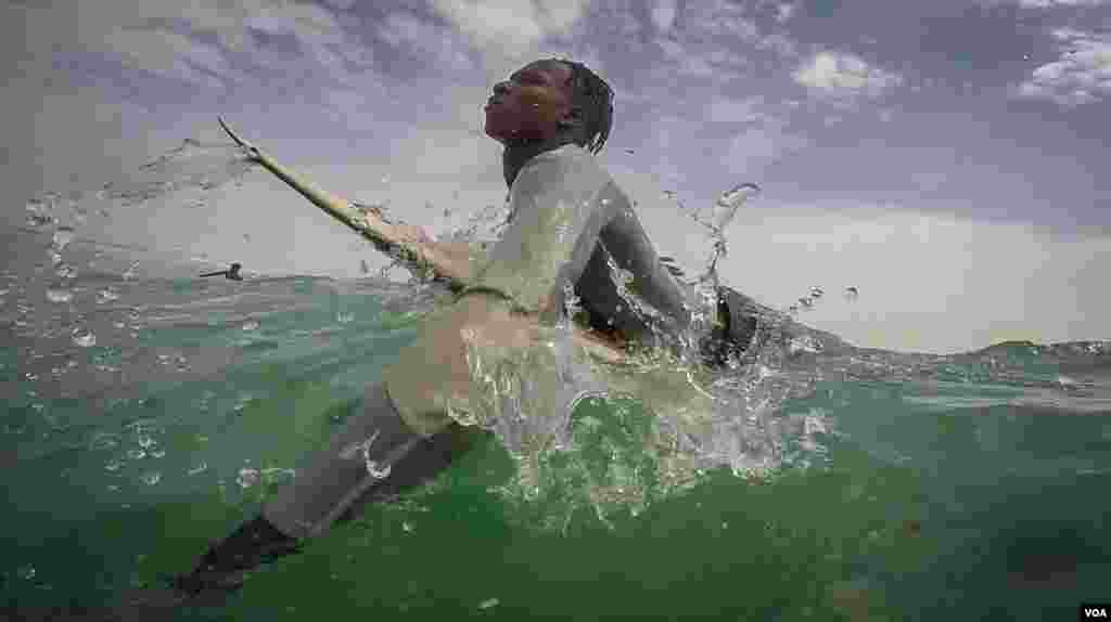 Pape Diouf paddles for a wave in waters off Dakar, Senegal. (Annika Hammerschlag/VOA)
