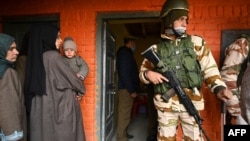 FILE - An Indian paramilitary soldier stands guard as voters stand in a queue to cast their ballots during the District Development Council and Panchayat by-elections at a polling station in Najan Sumbal area of Bandipora district, Dec. 1, 2020.