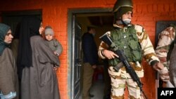 FILE - An Indian paramilitary soldier stands guard as voters stand in a queue to cast their ballots during the District Development Council and Panchayat by-elections at a polling station in Najan Sumbal area of Bandipora district, Dec. 1, 2020.