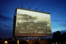 Foto dari Pembantaian Ras Tulsa ditayangkan di layar dalam pemutaran film documenter untuk memperingati 100 tahun penghancuran komunitas warga Kulit Hitam di Tulsa, Oklahoma, 26 Mei 2021.