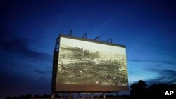 FILE - An image of devastation from the Tulsa Race Massacre is shown on a drive-in movie screen during a screening of documentaries for centennial commemorations of the destruction of a Black neighborhood in Tulsa, Oklahoma, May 26, 2021. 