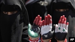 Yemeni female protesters show their hands with colors of the pre-Gadhafi Libya, Yemen and Syria flags during a demonstration demanding the resignation of Yemeni President Ali Abdullah Saleh in Sana'a, Yemen, October 21, 2011.
