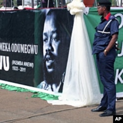 A security official stands next to a poster bearing the photograph of Biafran ex-warlord Lieutenant Colonel Odumegwu Ojukwu during a national funeral ceremony in Nigeria's southeastern city of Enugu, March 1, 2012