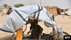 Displaced people fleeing from Boko Haram incursions into Niger are pictured under a makeshift tent in a camp near Diffa on June 16, 2016