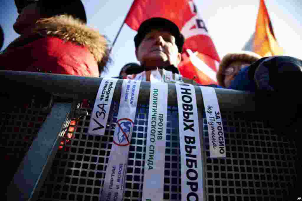 A protester draped white ribbons with slogans calling for fair elections and a Russia without Putin - over the police barricade at the rally. White ribbons have become a symbol of Russia's new protest movement. (VOA - Yuli Weeks)