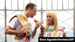 Eleven-time and defending men's champion Joey Chestnut, left, and defending women's champion Miki Sudo pose together during Nathan's Famous international Fourth of July hot dog eating contest the Empire State Building, July 3, 2019, in New York. 